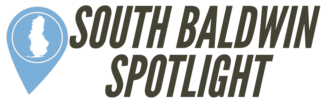 South Baldwin Spotlight logo with a blue map pin icon featuring a white landmass, next to bold text reading “South Baldwin Spotlight” on a dark background.